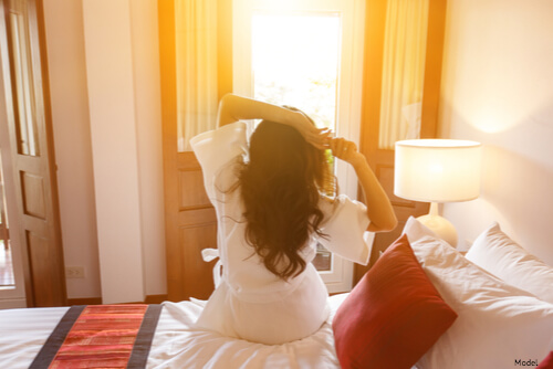 Woman sitting up in bed and stretching